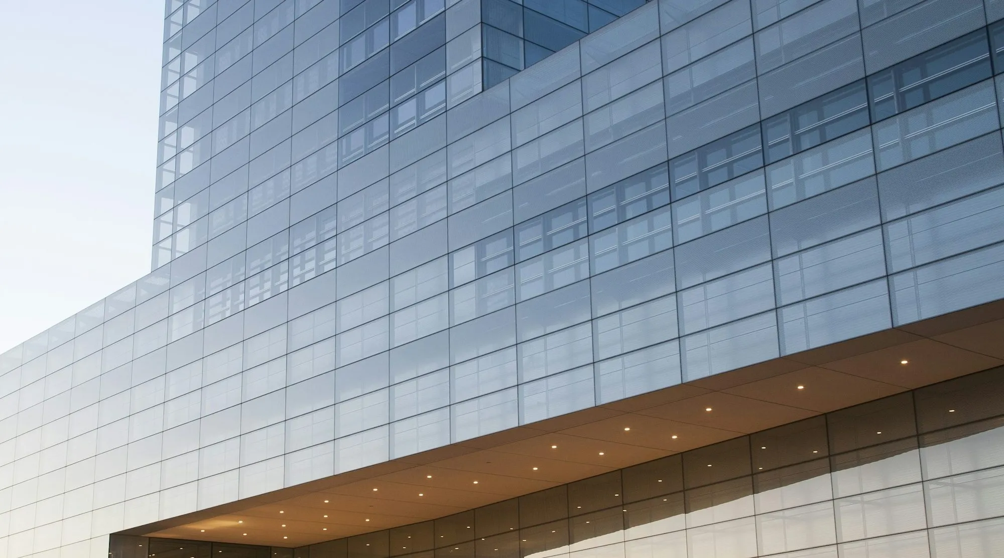 A modern glass office building at dusk with light trails from passing traffic